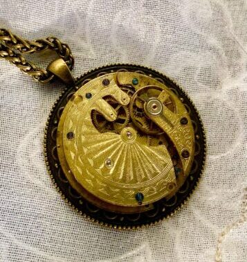 A handmade metal pendant with intricate golden details.