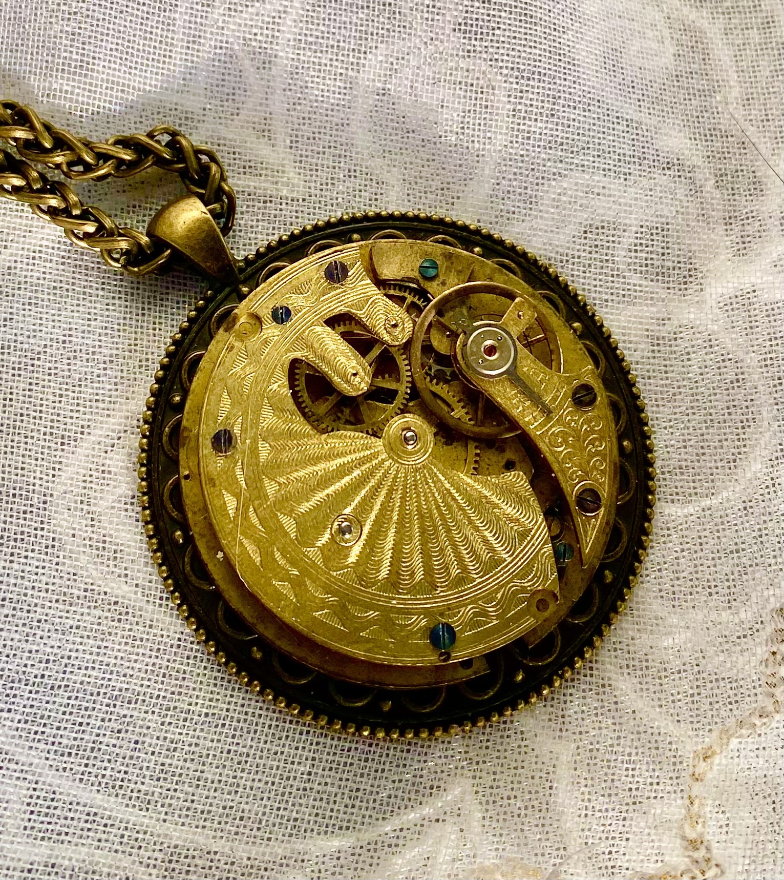 A handmade metal pendant with intricate golden details.