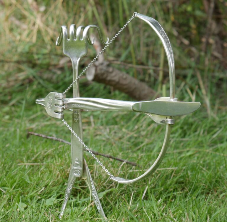 A figurine made of silverware drawing back a bow.