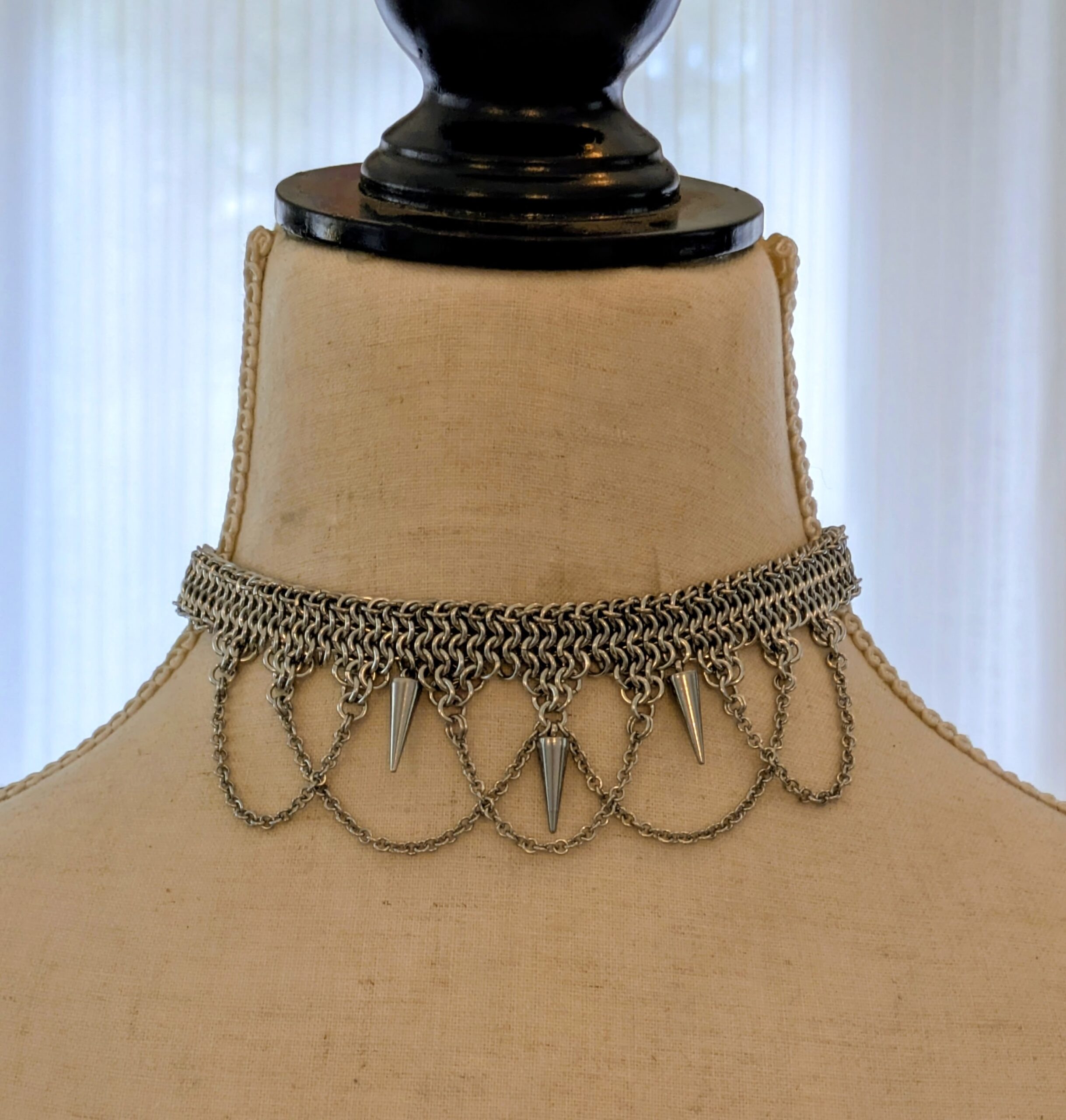 A handmade chainmail necklace on a mannequin.