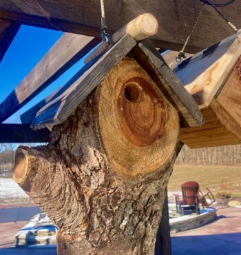 A handmade birdhouse made from a tree trunk.