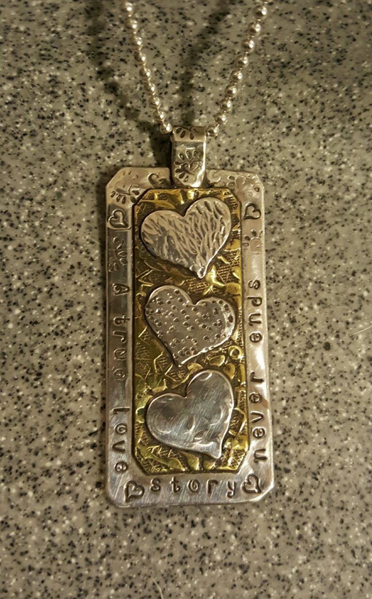 A handmade metal pendant with hearts on it.