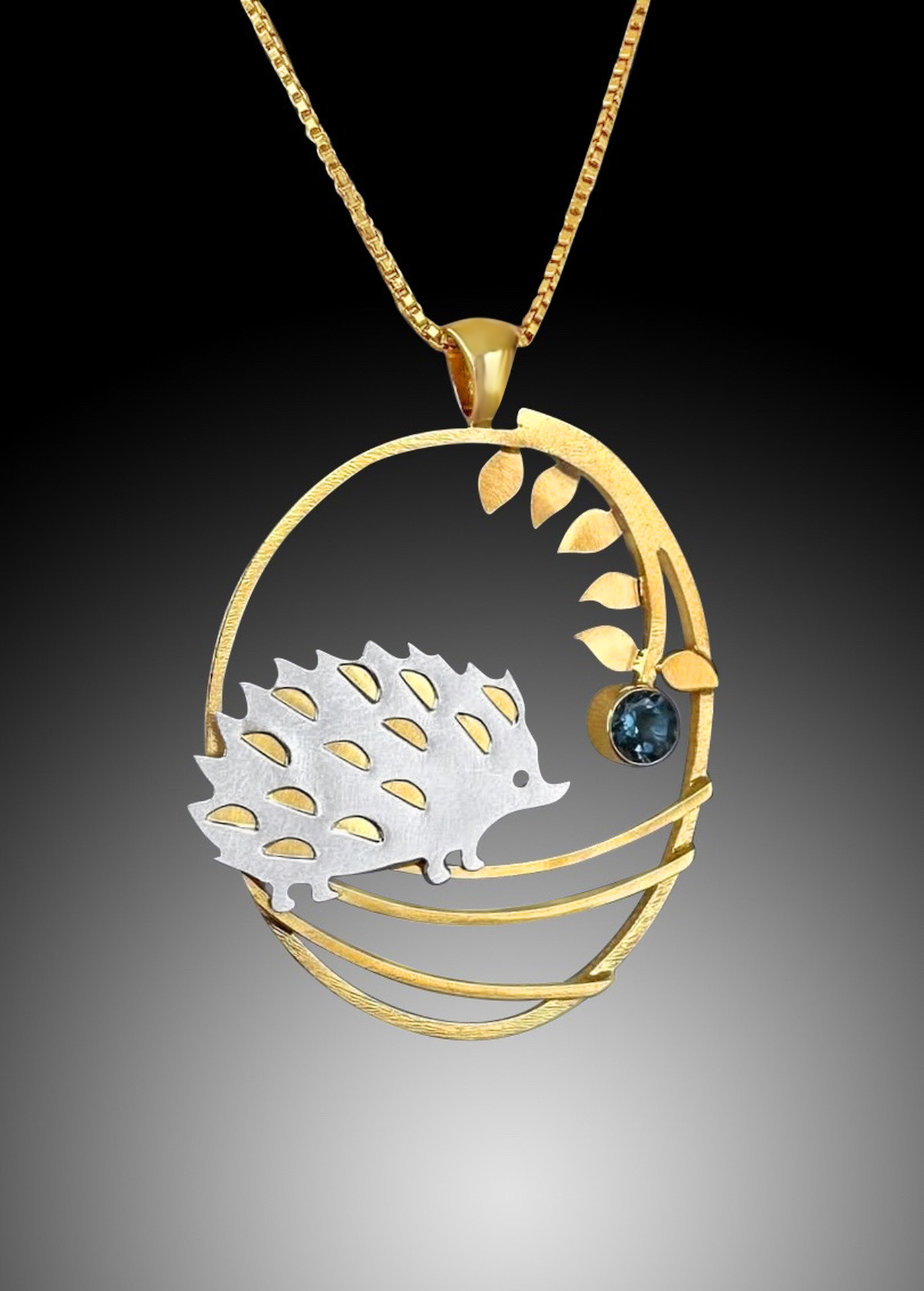 A necklace charm with a hedgehog and a plant placed inside.