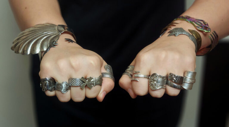 Two fists with handmade rings on each finger.