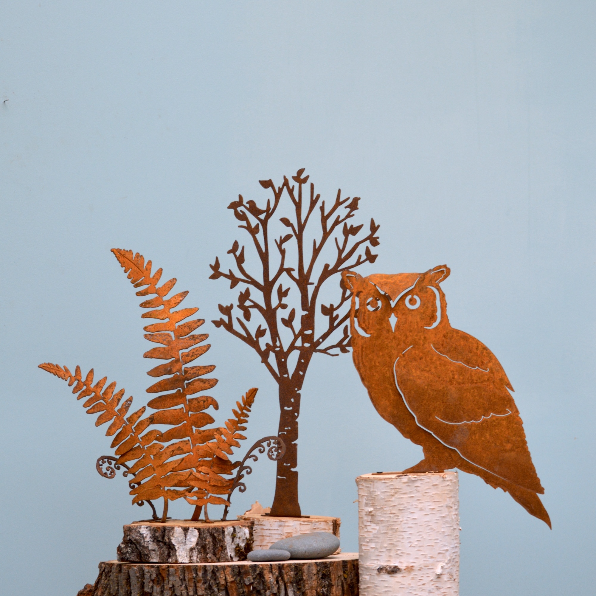 Decorative metal sculptures of a plant, a tree, and an owl.