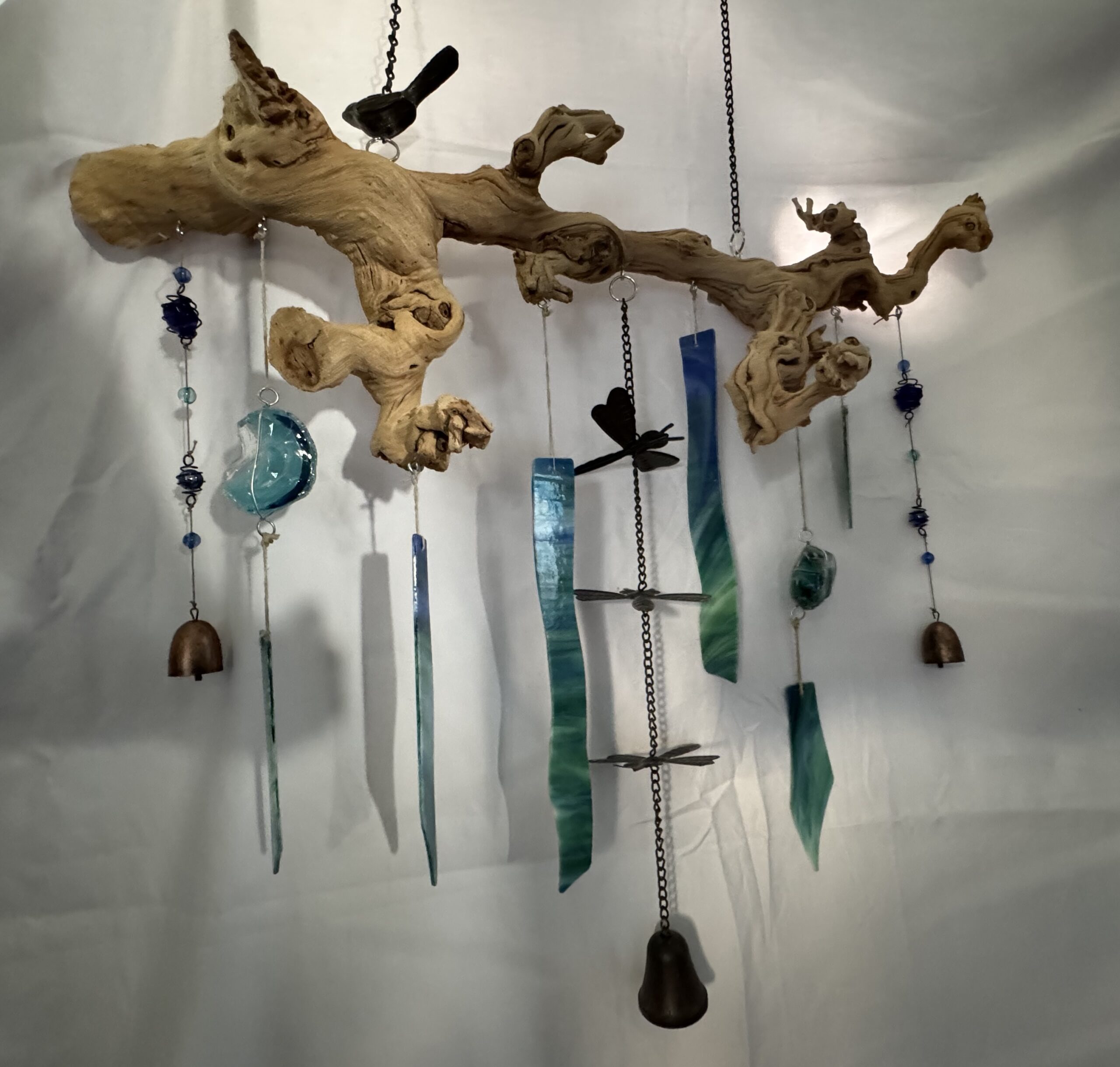 Various pieces of stained glass hanging from a severed tree branch.