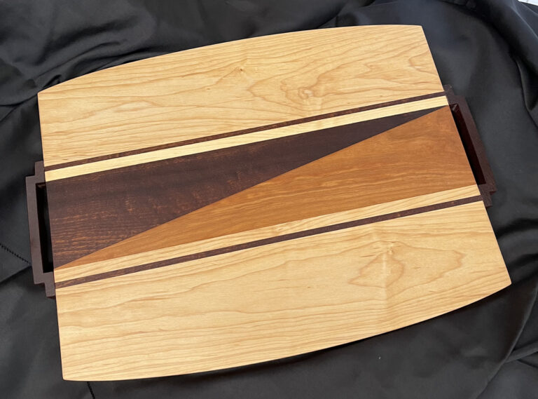 A wooden cutting board with an abstract design in the center.