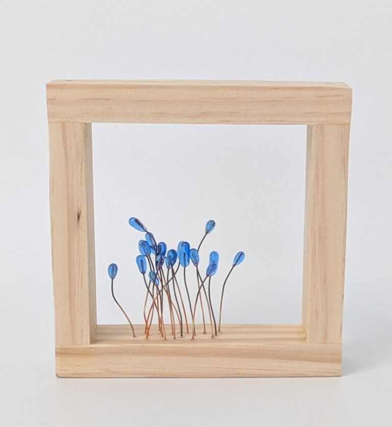 A piece of glass art in a wood frame.