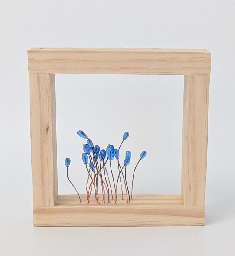 A piece of glass art in a wood frame.